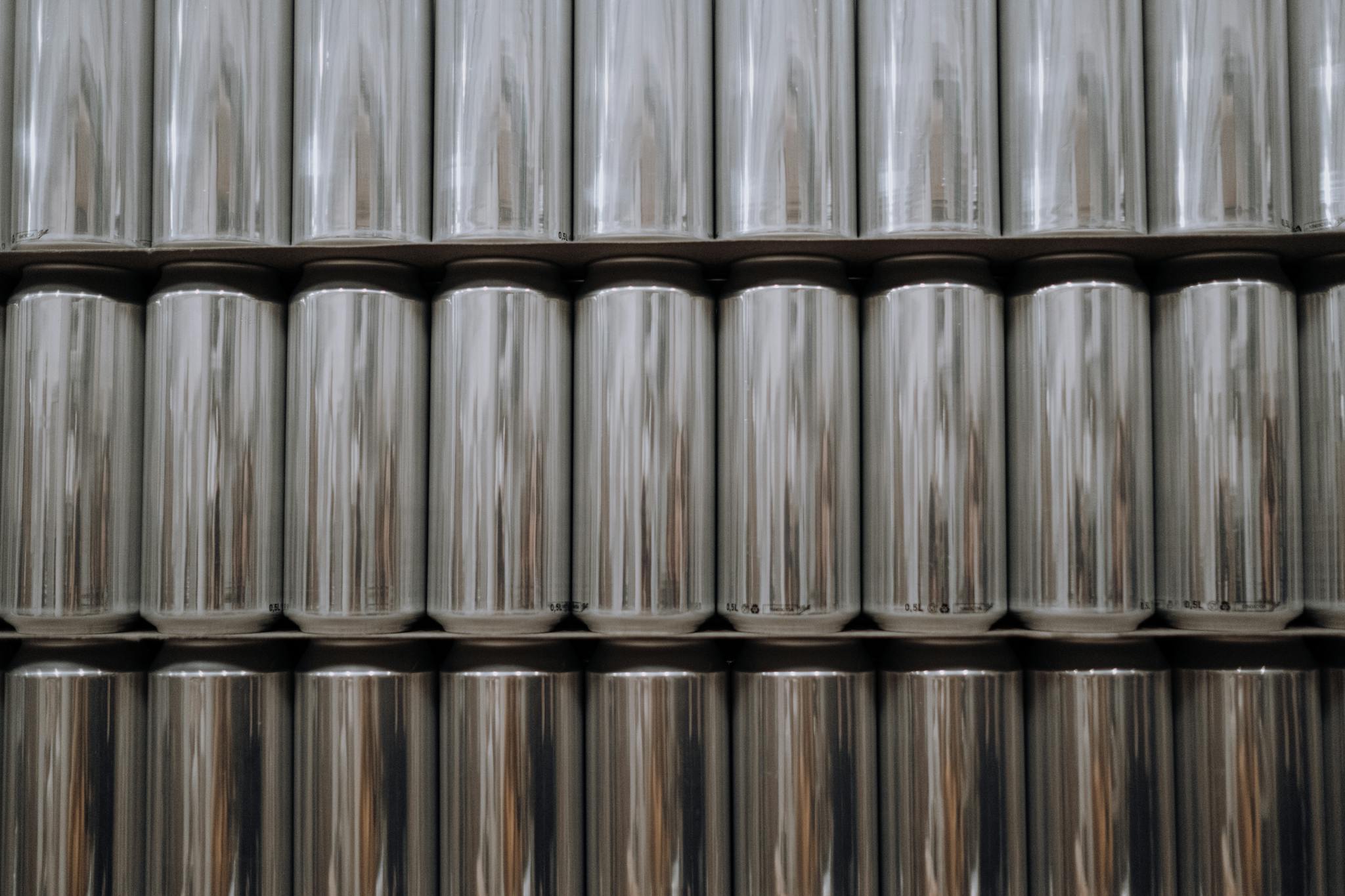 A neatly organized stack of reflective aluminum beverage cans in an industrial setting.